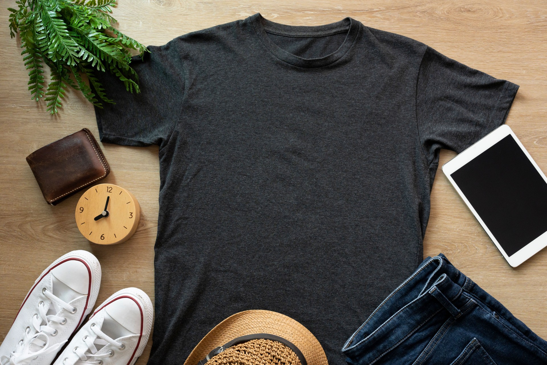 Mockup of a black t-shirt blank shirt template with accessories on the wooden table background, lifestyle and travel concept